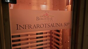 Un sauna en bois avec une pancarte indiquant « SAUNA À RAYONS INFRAROUGES 50° ».