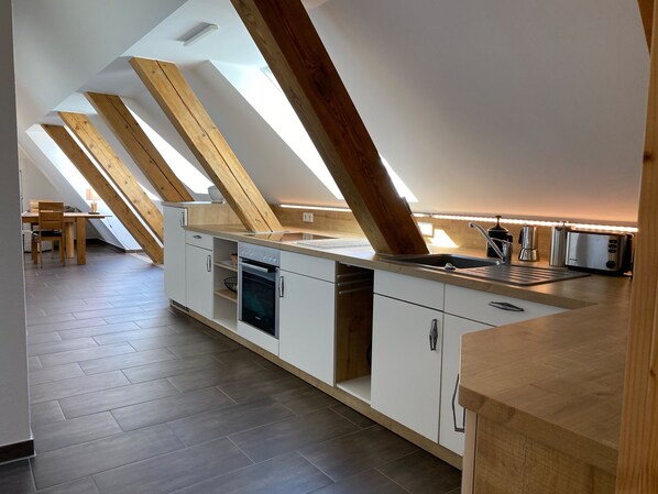 A modern kitchen with skylights, a built-in oven, and a toaster.