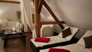 Une pièce confortable avec deux lits, un canapé, une table avec une bougie et une vue sur l’extérieur.