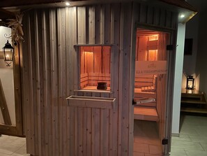 A wooden sauna with a bench and a hanging pot, a sign indicating it's a 60-degree sauna, and a lantern on the wall.