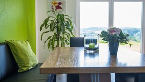 A dining table with a candle, a potted plant, and a view of the outdoors. - Ferienhof - Weites - Land, large apartment with terrace, garden and children's playground (Stadtkyll)