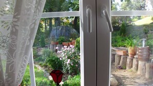 A window with a view of a garden, including potted plants and a rose. - Modern apartment in spacious villa, 3,000 sqm property, south-facing slope, forest, WIFI (Michendorf OT Wilhelmshorst)
