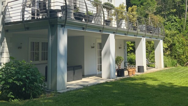 A large, white building with a covered outdoor area and a well-maintained lawn. - Modern apartment in spacious villa, 3,000 sqm property, south-facing slope, forest, WIFI (Michendorf OT Wilhelmshorst)