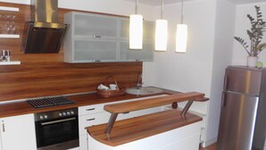 A modern kitchen with a wooden countertop, stainless steel appliances, and pendant lighting. - Modern apartment in spacious villa, 3,000 sqm property, south-facing slope, forest, WIFI (Michendorf OT Wilhelmshorst)