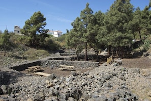 A rocky outdoor area with stone walls, picnic tables, and trees.