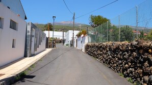 Eine enge Straße mit weißen Häusern, einer Steinmauer und blauem Himmel.