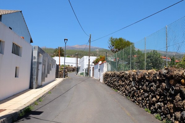 A narrow street with white buildings, a stone wall, and a clear blue sky. - Casa Samuel, rural escape with pool, Las Vegas village (Granadilla de Abona)