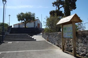 Un muro de piedra, un letrero de madera y un edificio con la leyenda 'CANAL' al fondo.