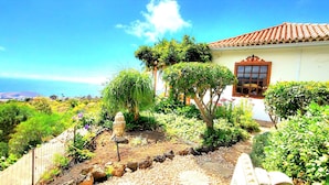 A garden with a Buddha statue, a house with a red-tiled roof, and a view of the ocean. - Großzüg. House with panoramic views of sea, mountains & valley + optional apartment (Tajuya)
