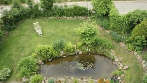 Um jardim com lago, banco e diversas plantas.