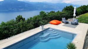 Un espace piscine offrant une vue sur les montagnes et un lac.