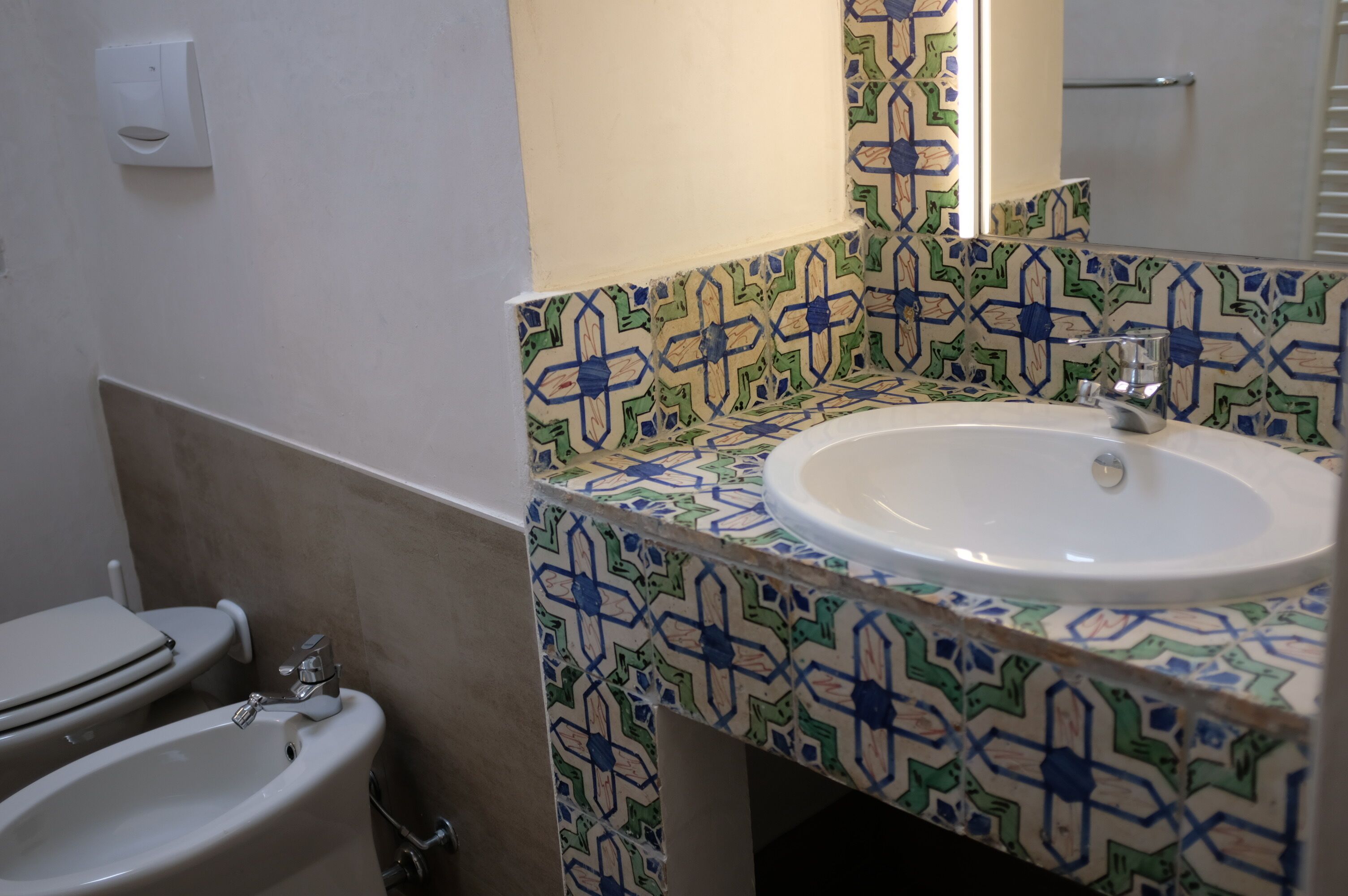 A bathroom with a white sink, a mirror, and a toilet.