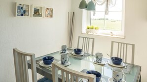 Una mesa de comedor con sillas, vajilla de diseño azul y blanco, y cuadros colgados en la pared.