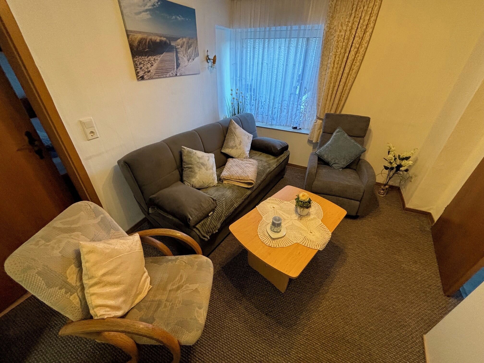 Een woonkamer met een bank, fauteuil en salontafel.