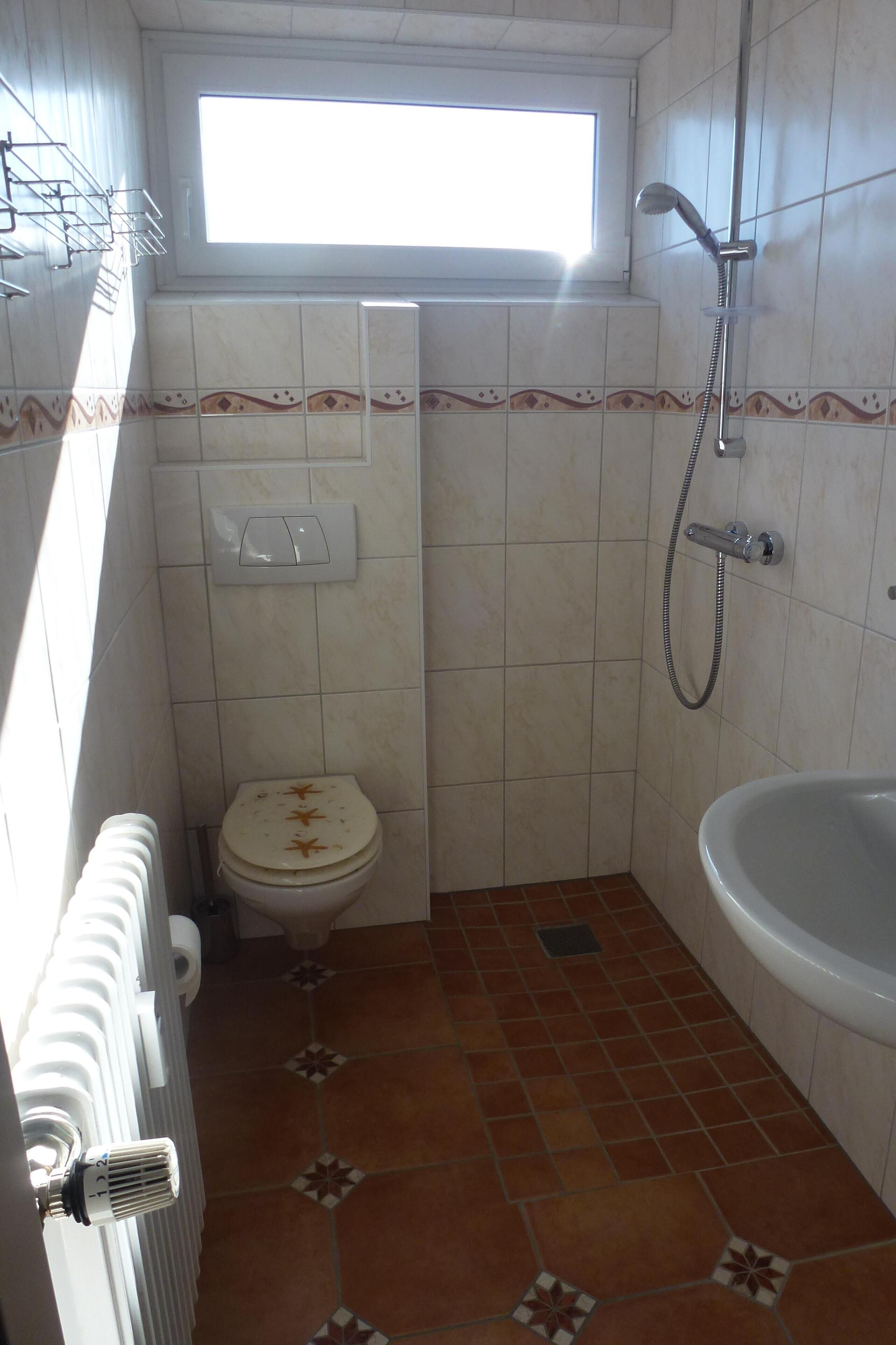 Een kleine badkamer met toilet, douche en bad.