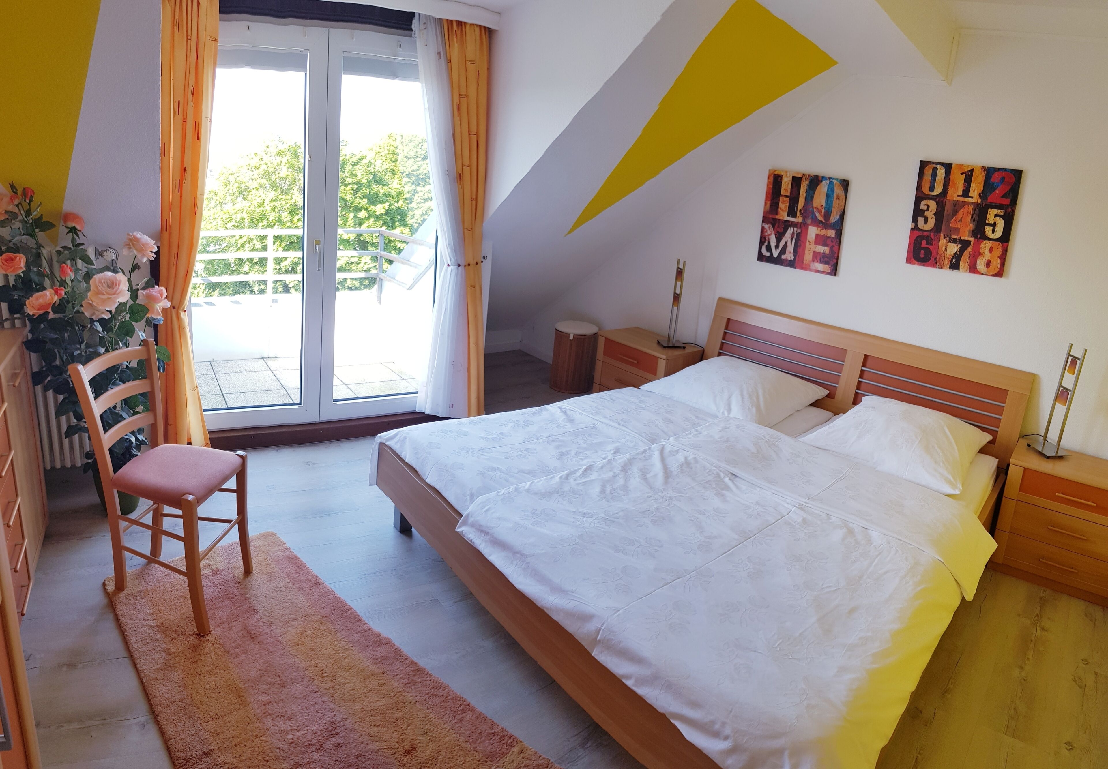 A bedroom with a bed, a chair, a nightstand, and a window with curtains.