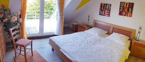A bedroom with a bed, a chair, a nightstand, and a window with curtains.