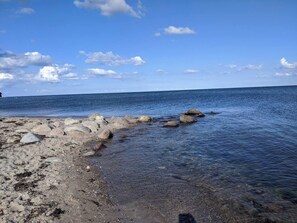 Eine felsige Küstenlinie mit klarem Wasser und einem teilweise bewölkten Himmel.