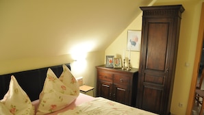 A bedroom with a bed, pillows, a dresser, and a cabinet.