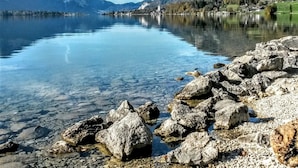 A clear lake with rocky shoreline and distant mountains.
