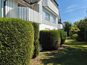 A modern two-story building with a white exterior and a well-maintained garden.