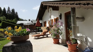 Eine Terrasse mit Liegestuhl, Blumentöpfen und Schornstein.