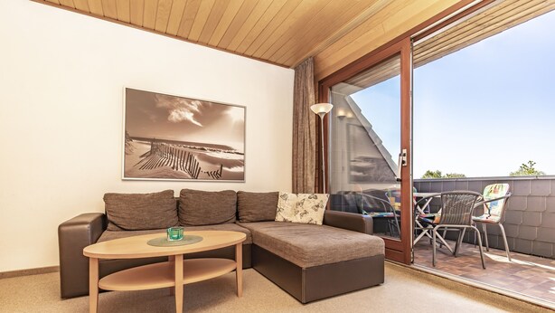 A modern living room with a sectional sofa, a small round table, and a large window offering a view of the outdoors.