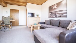 A modern living room with a sofa, a television, a small table, and a chair.