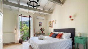 A bedroom with a large bed, a green nightstand, and a view of greenery through a glass door. - Private sunny villa with large heated pool, air-conditioning and river access. (Céret)