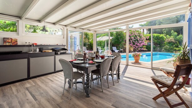 A modern kitchen with a dining area, large windows, and a view of a swimming pool. - Private sunny villa with large heated pool, air-conditioning and river access. (Céret)