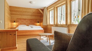 A cozy wooden cabin room with a bed, a small table, and a sofa. - Harzer Wiesenbaude - Holiday home with sauna and hot tub in a secluded location. (Braunlage)