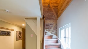 A staircase with wooden steps and exposed brick walls, leading to a landing with a white door. - Harzer Wiesenbaude - Holiday home with sauna and hot tub in a secluded location. (Braunlage)