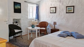 Una camera da letto con un letto, una sedia, un tavolino, una lampada e un armadietto.