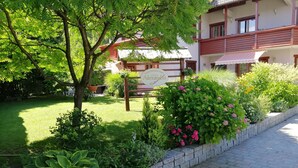 Un jardín bien cuidado con diversas plantas y un cartel que indica una propiedad llamada 'Alexandra'.
