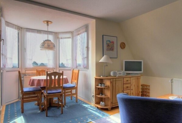 Una habitación acogedora con una mesa de comedor, sillas, un televisor y una lámpara.