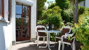An outdoor patio with a table and chairs, a wine bottle, and a wine glass.