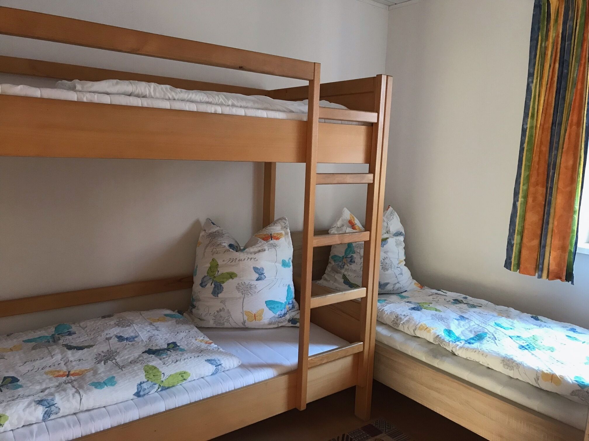 Une chambre avec un lit superposé, dotée de draps et d’oreillers à motifs floraux.