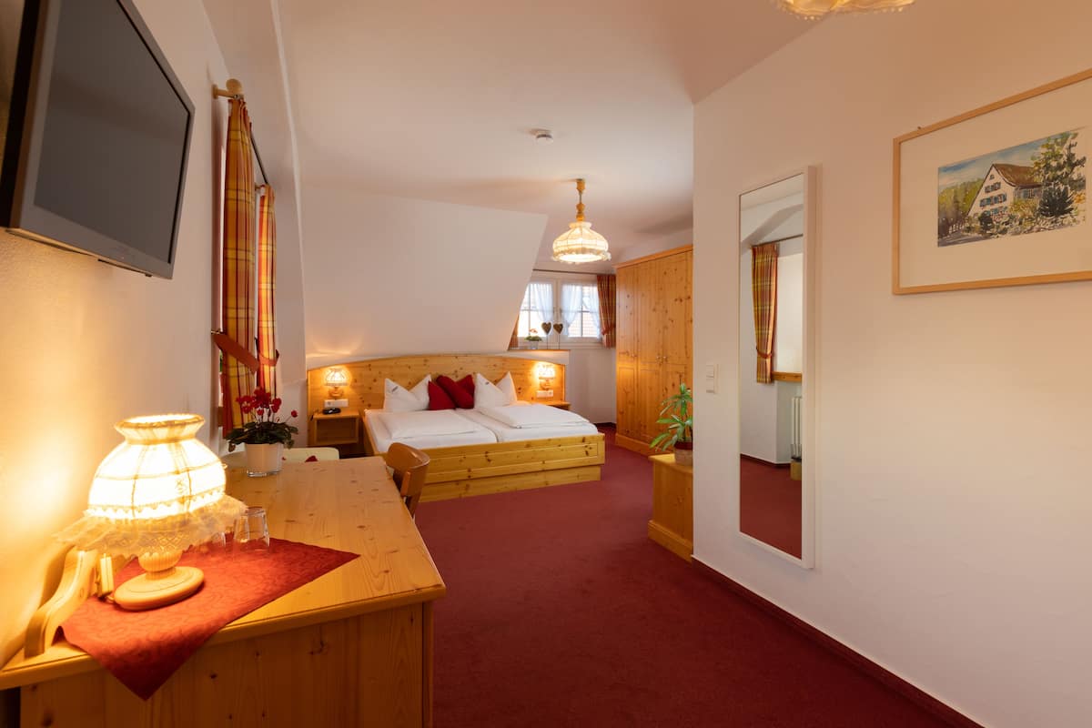 Ein Schlafzimmer mit einem Holzbett, einem Schreibtisch mit Lampe, einem Spiegel und einem Bild an der Wand.
