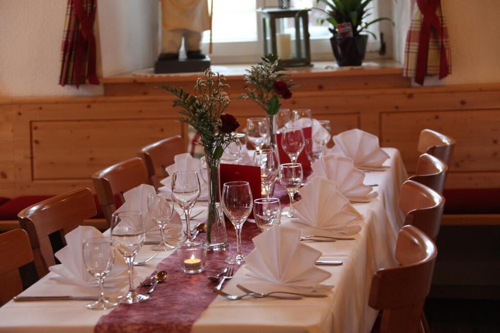 A long dining table set with white tablecloths, glassware, and candles.