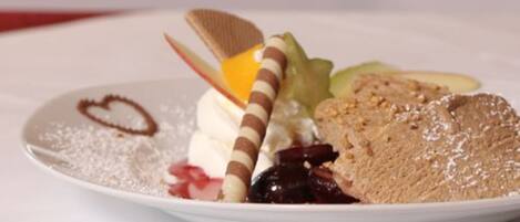 Un plato de postre con varios elementos, como una galleta cubierta de chocolate, crema batida y una porción de pastel.