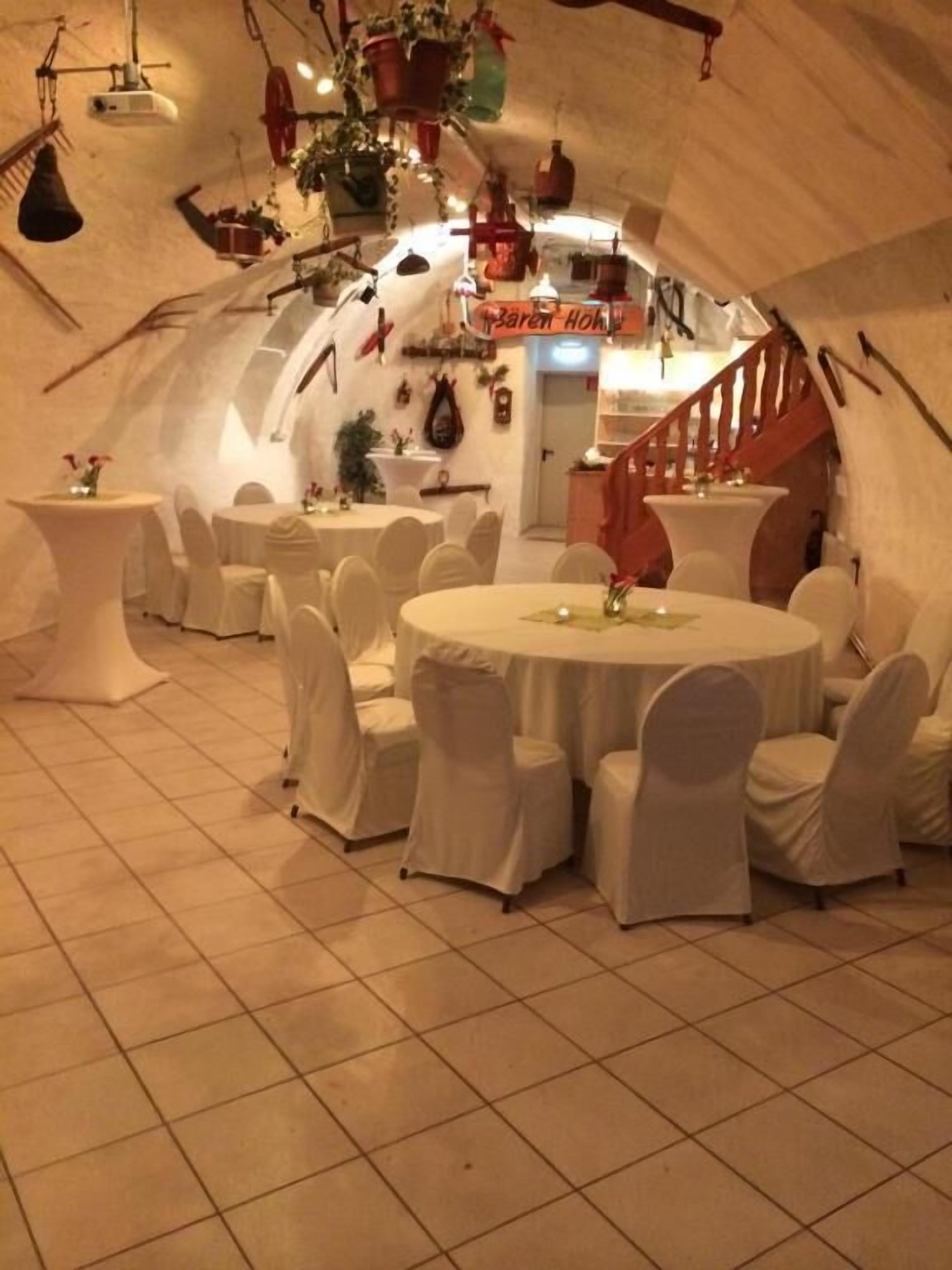 Un interior con mesas y sillas redondas, una escalera y un letrero que dice "Sarah's Home".