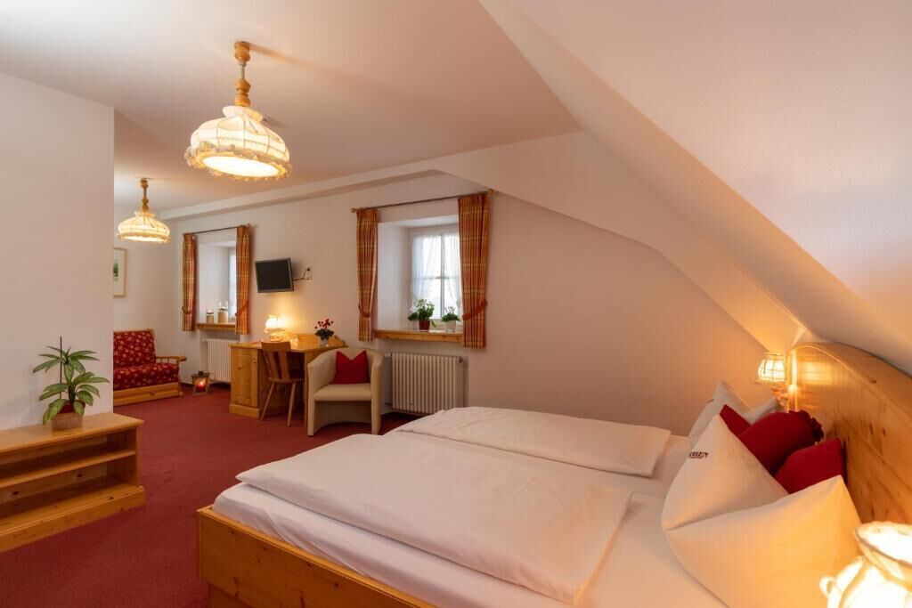 A cozy hotel room with a large bed, a desk, a chair, and a television.