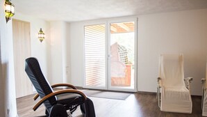 A room with a sliding glass door, a black office chair, a white chair, and a small table. - Ferienhof - Weites - Land, large apartment with terrace, garden and children's playground (Stadtkyll)