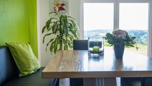 A dining table with a candle, a potted plant, and a view of the outdoors. - Ferienhof - Weites - Land, large apartment with terrace, garden and children's playground (Stadtkyll)