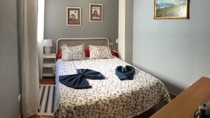A neatly made bed with a patterned bedspread, two framed pictures on the wall, and a painting above the bed. - Nice apartment 75 m from the sea (Arico)