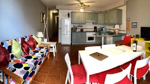 A compact living space with a dining area, kitchen, and a sofa with colorful cushions. - Nice apartment 75 m from the sea (Arico)
