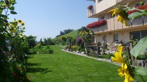 Un hotel con vista a un jardín, un balcón con jardineras y cielo despejado.