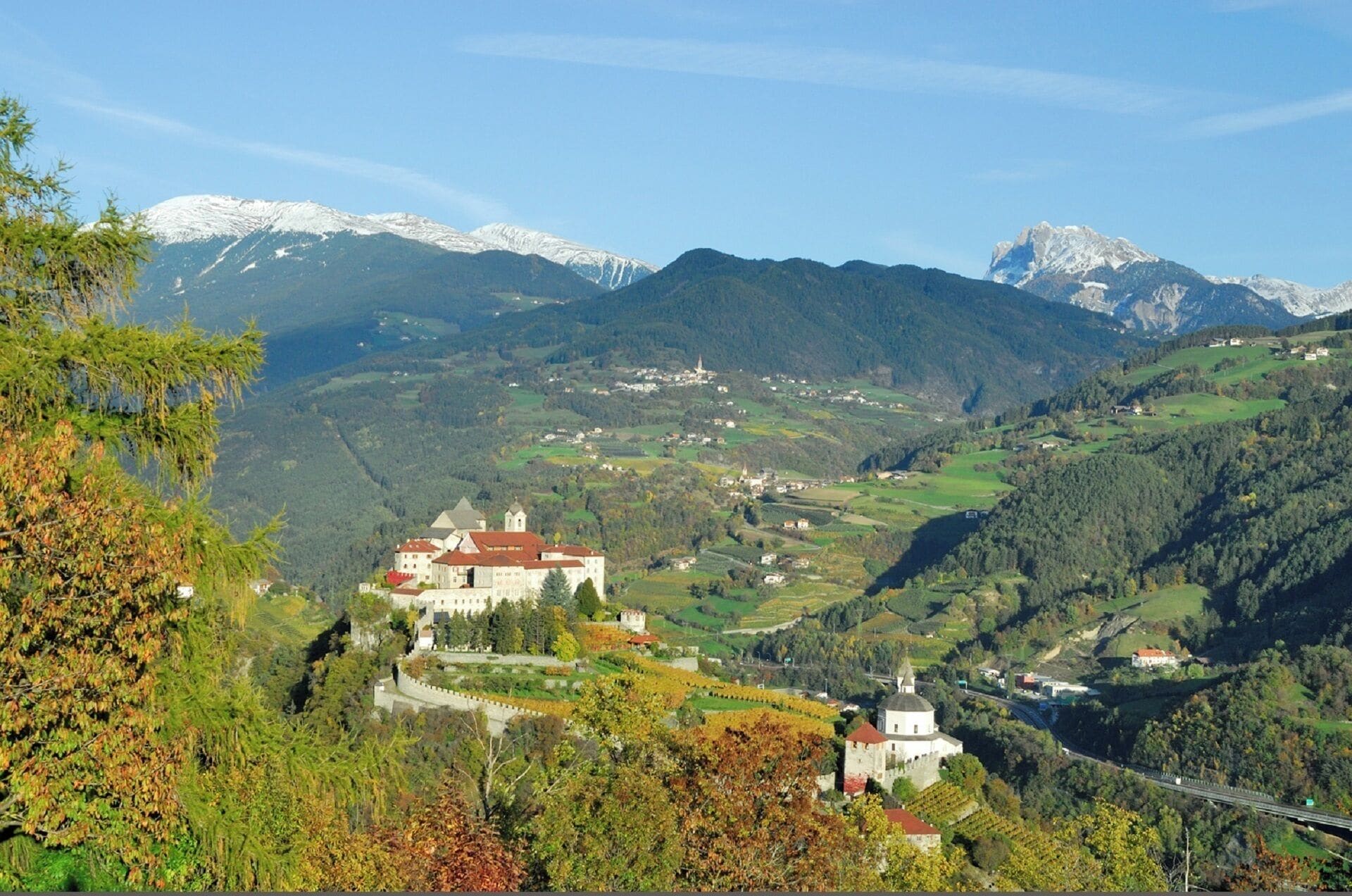Un castillo rodeado de abundante vegetación y montañas.