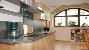A kitchen with a built-in stove, a coffee maker, and a window with plants. - Apartment "Bauernstube" with pool and sauna use on a restored 3 side courtyard (Meißen)