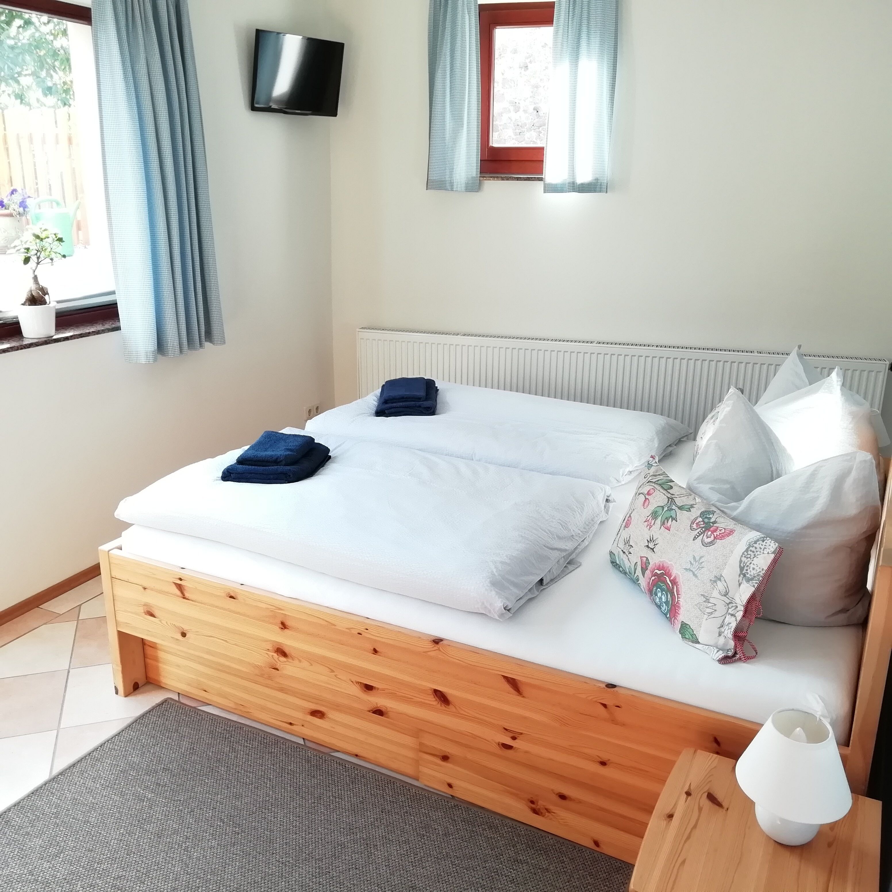 A neatly made bed with white and blue bedding, a wooden headboard, and a small bedside table with a lamp.